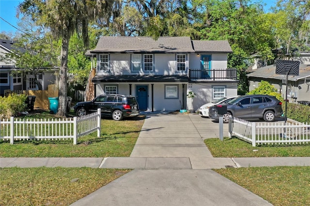 view of front facade with a fenced front yard, a front yard, driveway, and stucco siding