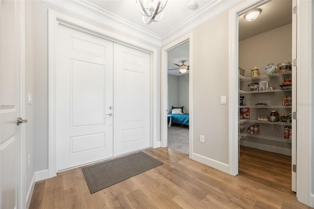 foyer with light wood finished floors, baseboards, and crown molding