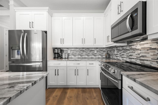 kitchen with dark wood finished floors, stainless steel appliances, tasteful backsplash, white cabinets, and light stone countertops