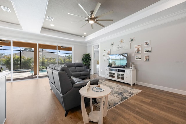 living room featuring visible vents, a raised ceiling, a sunroom, and a ceiling fan