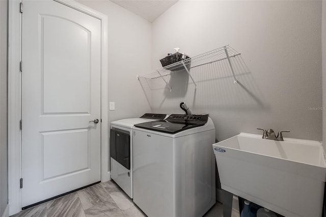 laundry area with laundry area, washing machine and dryer, marble finish floor, and a sink