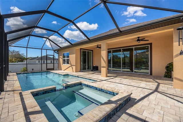 view of pool with glass enclosure, a patio area, a pool with connected hot tub, and a ceiling fan