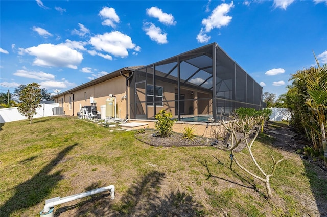 rear view of property featuring a yard, stucco siding, a fenced backyard, and a lanai