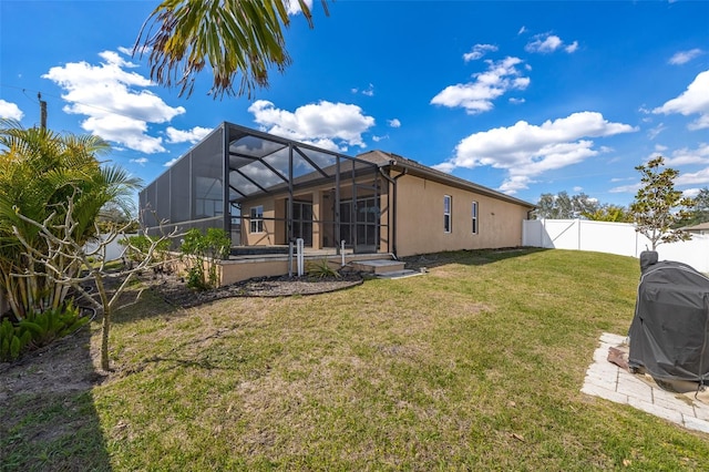 rear view of property featuring a lanai, a fenced backyard, a lawn, and stucco siding