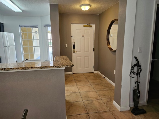 entrance foyer featuring light tile patterned flooring, baseboards, and a textured ceiling