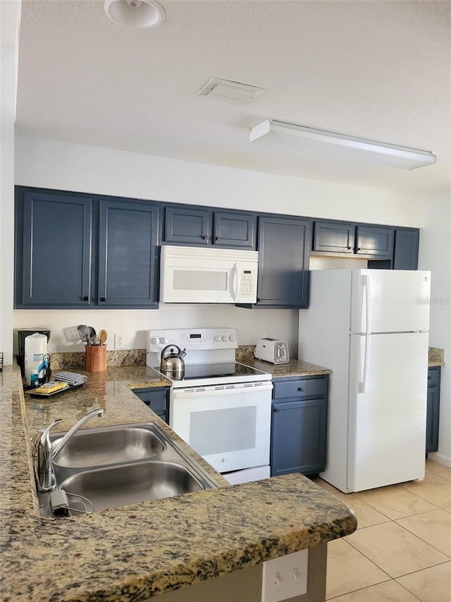 kitchen with visible vents, blue cabinetry, light tile patterned floors, white appliances, and a sink