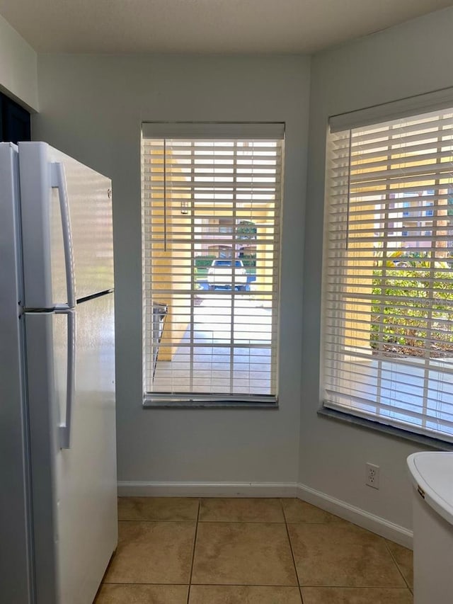 unfurnished dining area featuring light tile patterned floors and baseboards