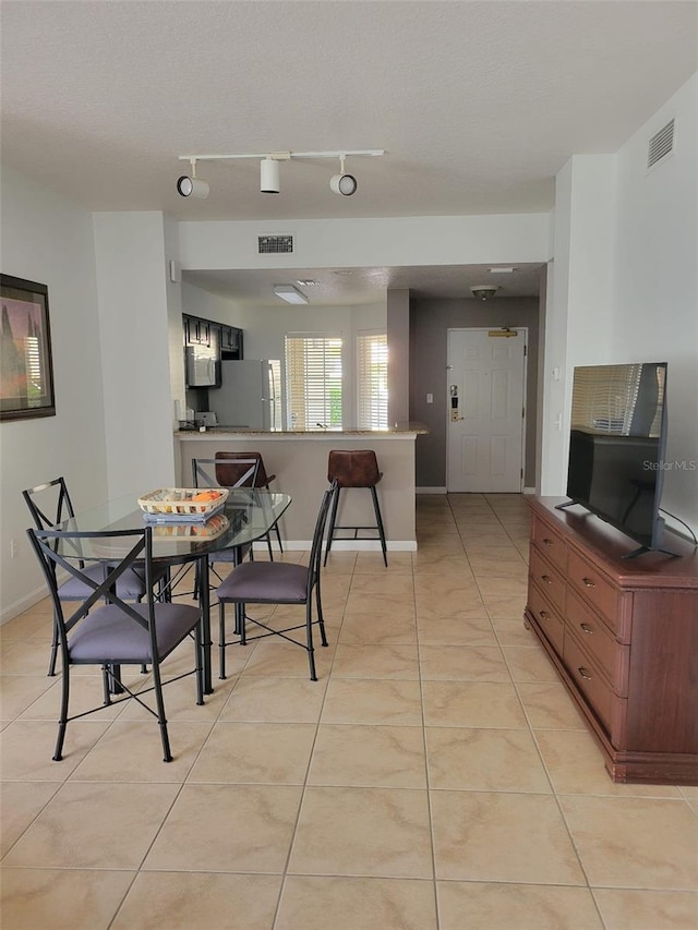 dining area featuring track lighting, light tile patterned floors, visible vents, and baseboards