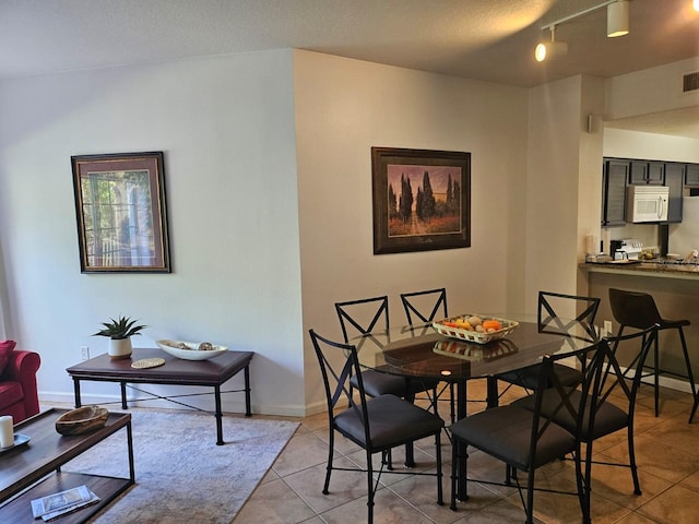 dining area with rail lighting, light tile patterned floors, baseboards, and visible vents