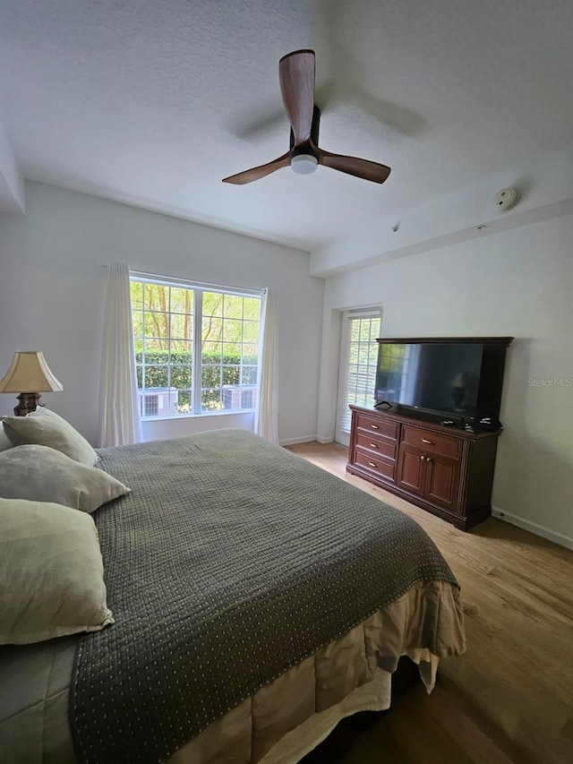 bedroom featuring baseboards, light wood-style flooring, and a ceiling fan