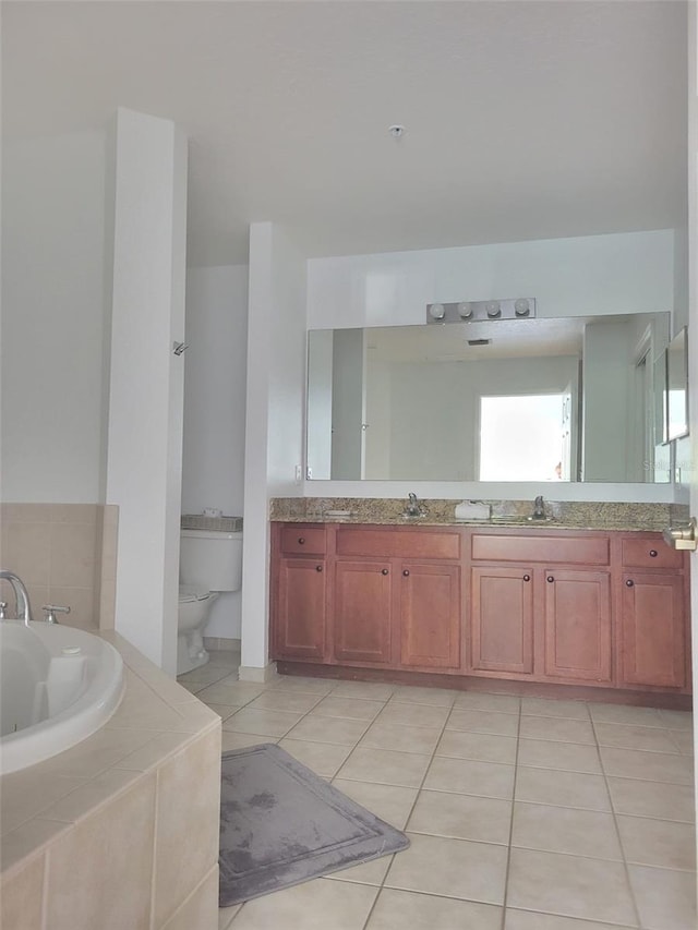 full bathroom featuring toilet, double vanity, tile patterned floors, a tub with jets, and a sink