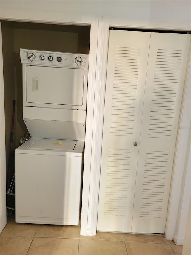 laundry room with light tile patterned flooring, stacked washer / dryer, and laundry area