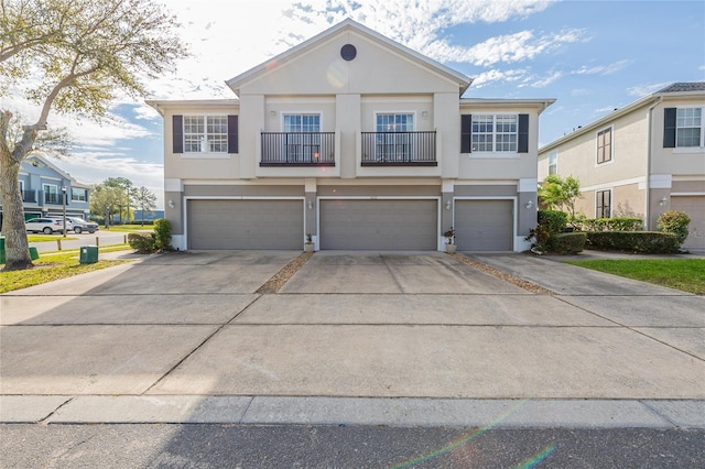 view of front of home with a balcony, a garage, driveway, and stucco siding