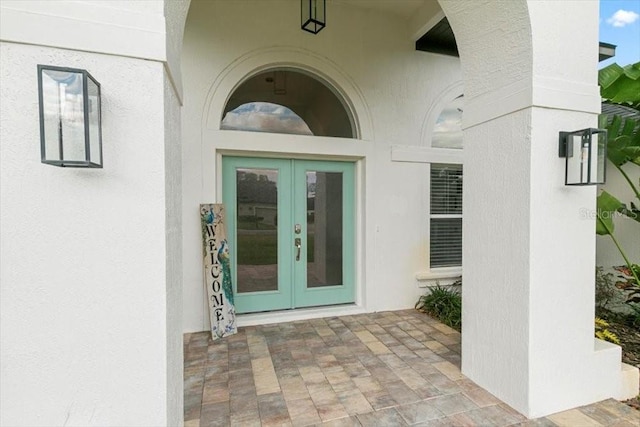 view of exterior entry with french doors and stucco siding