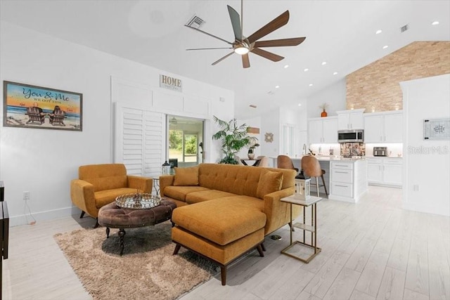 living area with light wood finished floors, visible vents, high vaulted ceiling, and a ceiling fan