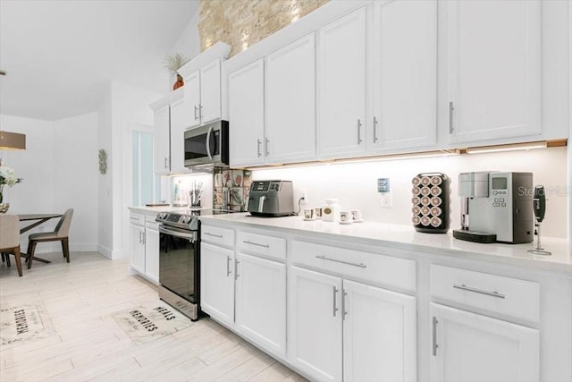 kitchen featuring stainless steel appliances, light countertops, light wood-style flooring, and white cabinets