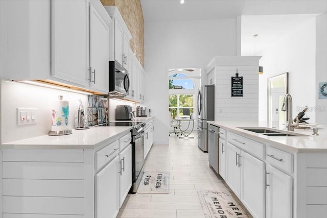 kitchen with stainless steel appliances, a sink, white cabinets, light countertops, and tasteful backsplash