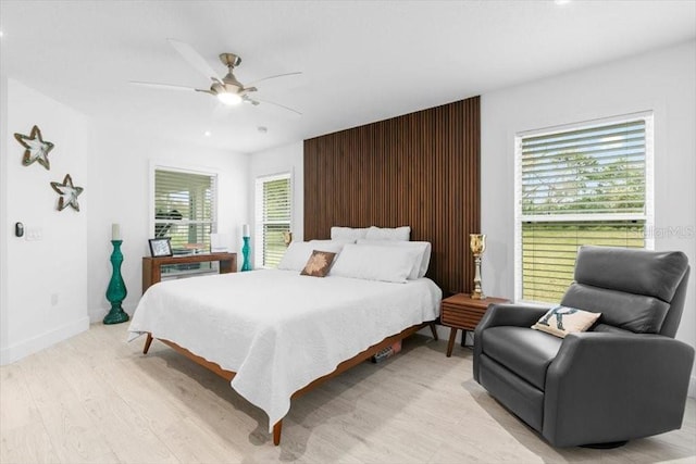 bedroom with light wood-style floors, ceiling fan, and baseboards