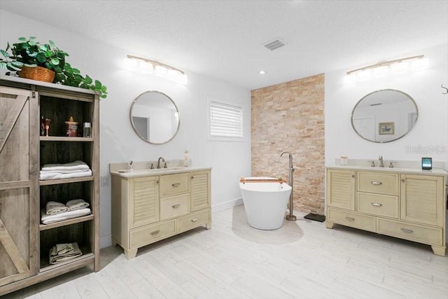 full bath with two vanities, a soaking tub, a sink, and visible vents