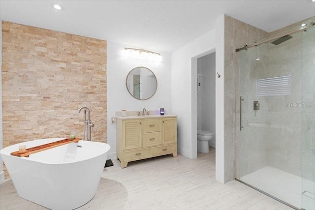 bathroom featuring toilet, a stall shower, a freestanding tub, and vanity