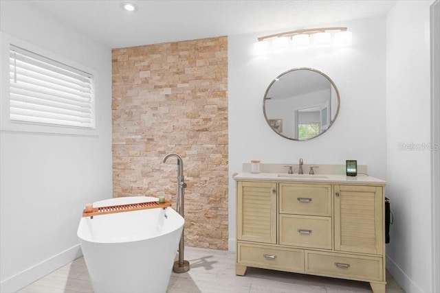 full bathroom with a freestanding tub, vanity, and baseboards