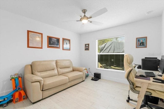 office featuring a ceiling fan, light wood-style flooring, and baseboards