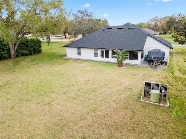 back of property featuring roof with shingles and a yard