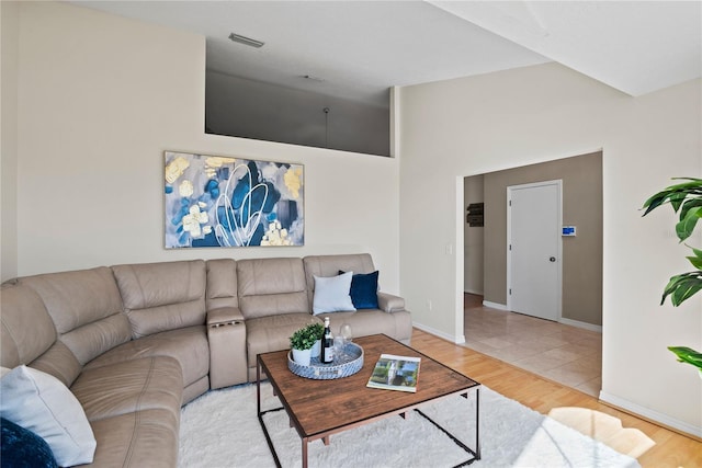 living room with visible vents, lofted ceiling, baseboards, and wood finished floors