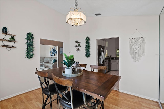 dining room featuring light wood-style flooring, baseboards, and a chandelier