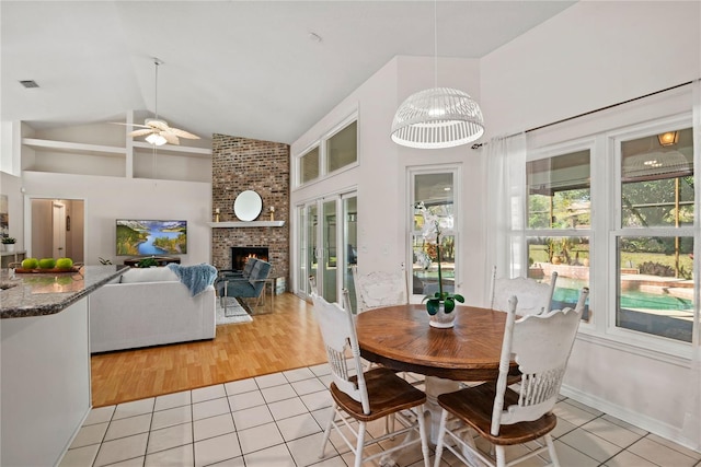 dining area with light tile patterned flooring, visible vents, a fireplace, and ceiling fan