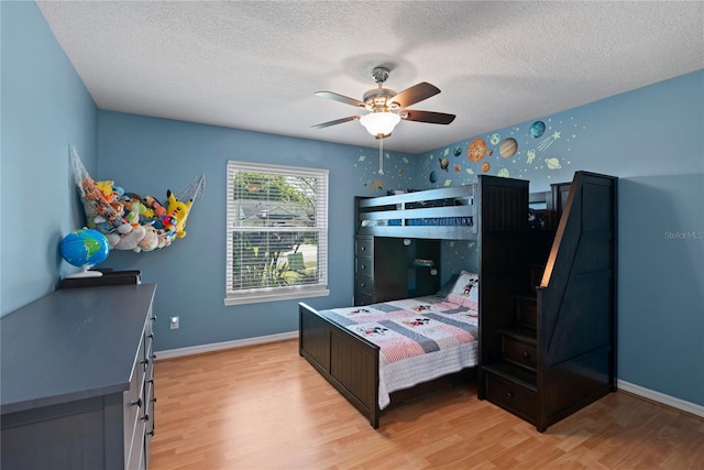 bedroom featuring light wood-style flooring, a ceiling fan, baseboards, and a textured ceiling