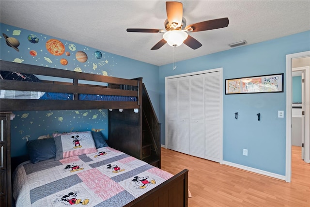 bedroom with visible vents, baseboards, wood finished floors, a closet, and a textured ceiling