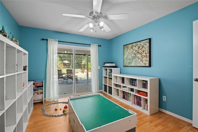 game room featuring baseboards, a textured ceiling, ceiling fan, and wood finished floors