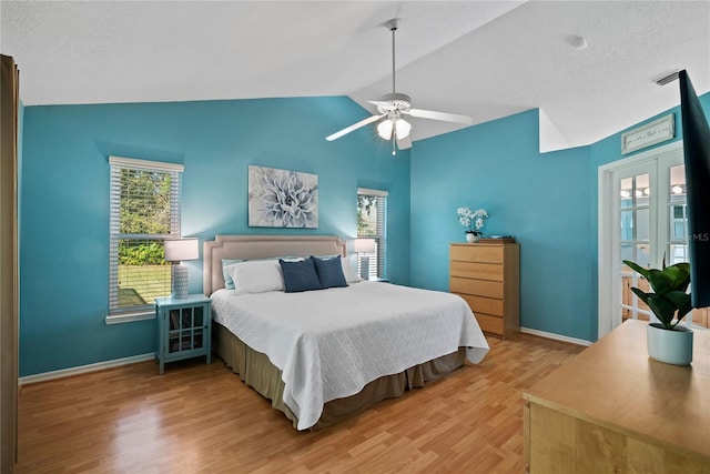 bedroom featuring lofted ceiling, multiple windows, wood finished floors, and baseboards