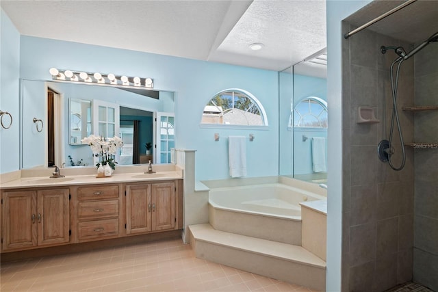 full bath featuring a tile shower, a textured ceiling, a garden tub, and a sink