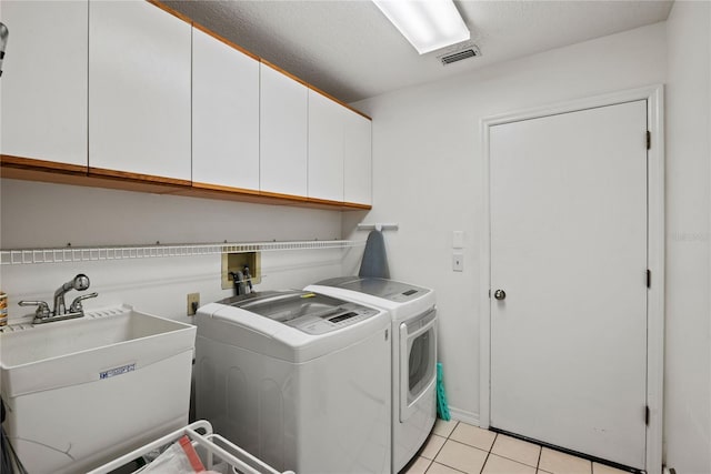 laundry room featuring visible vents, washing machine and clothes dryer, light tile patterned flooring, cabinet space, and a sink