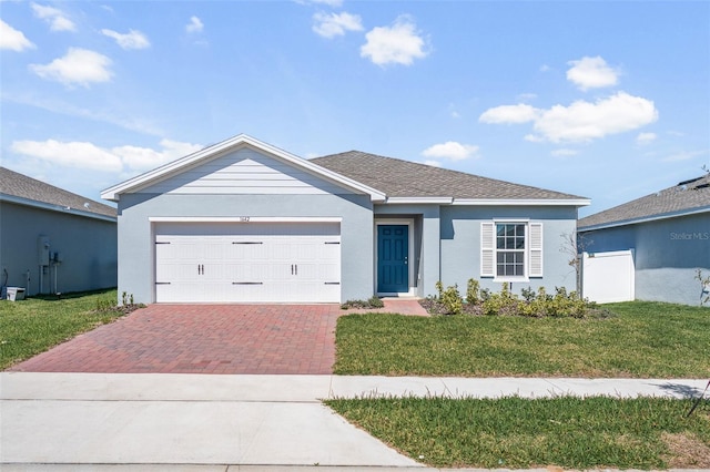 ranch-style home with decorative driveway, roof with shingles, stucco siding, an attached garage, and a front yard