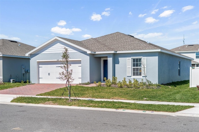 ranch-style home featuring a shingled roof, a front lawn, decorative driveway, and stucco siding