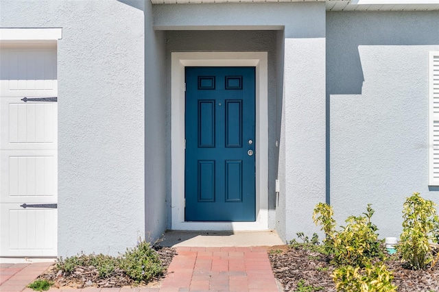 entrance to property featuring a garage and stucco siding