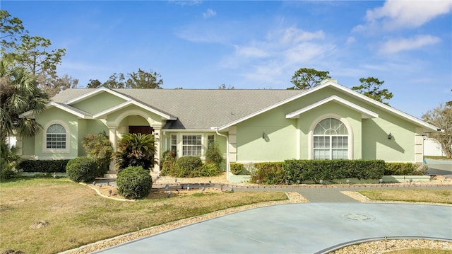 ranch-style home with driveway, a front lawn, and stucco siding