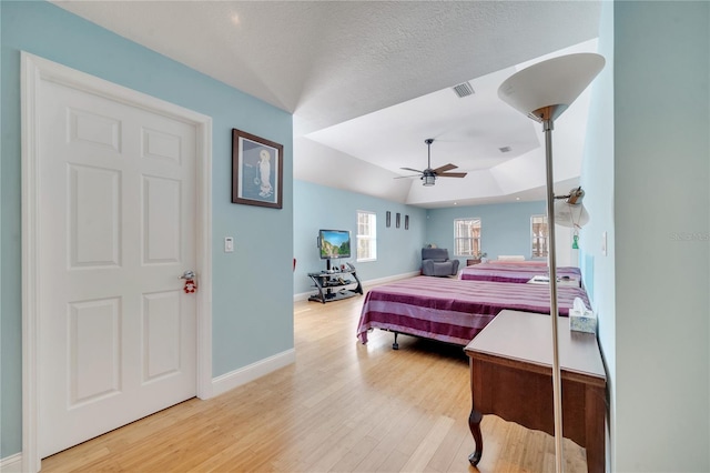 bedroom with baseboards, visible vents, ceiling fan, a textured ceiling, and light wood-style floors