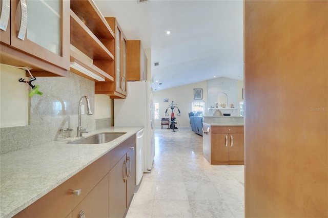 kitchen with lofted ceiling, glass insert cabinets, light stone counters, open floor plan, and a sink