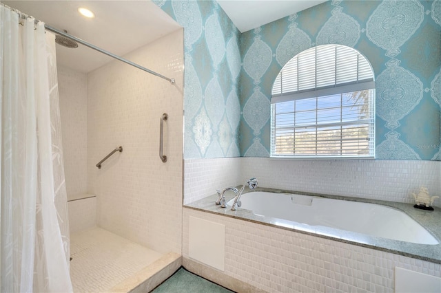 bathroom with a garden tub, a tile shower, and wallpapered walls