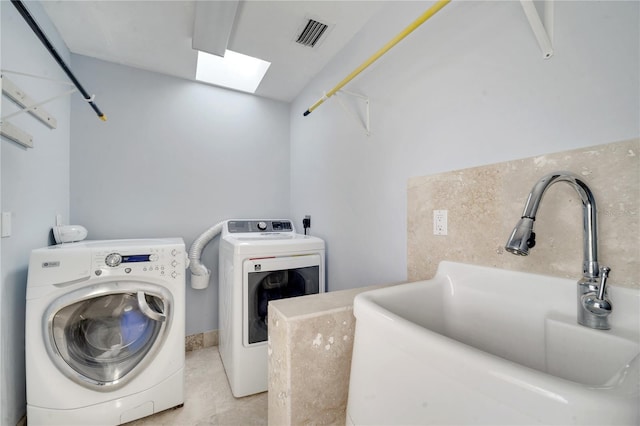 clothes washing area featuring laundry area, a skylight, visible vents, washing machine and dryer, and a sink