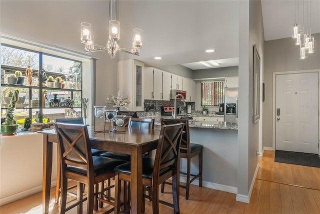 dining area with light wood-style floors, recessed lighting, baseboards, and an inviting chandelier