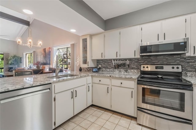 kitchen featuring lofted ceiling, light tile patterned flooring, a sink, appliances with stainless steel finishes, and decorative backsplash