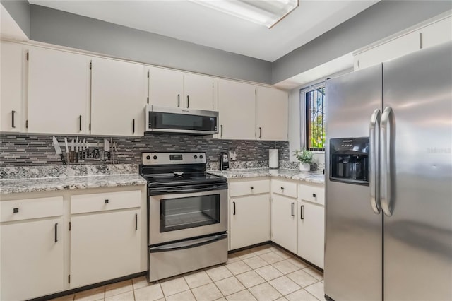 kitchen featuring stainless steel appliances, white cabinetry, decorative backsplash, and light tile patterned floors