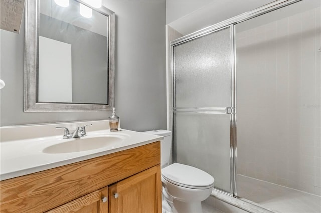 bathroom featuring a shower stall, toilet, and vanity