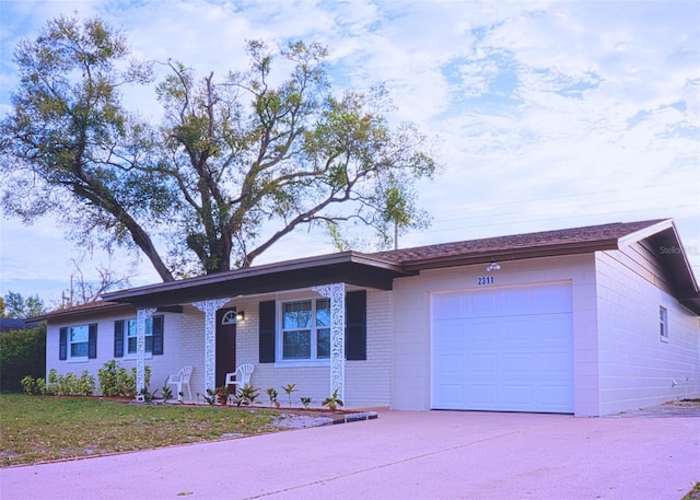 single story home with driveway, brick siding, and an attached garage