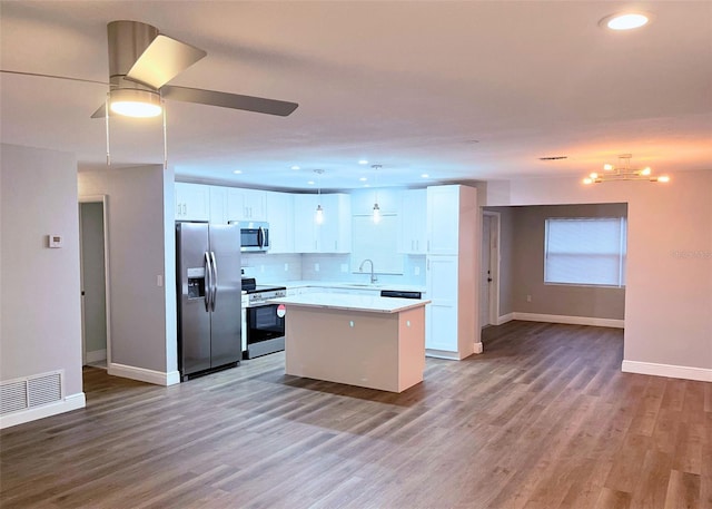 kitchen with visible vents, a kitchen island, appliances with stainless steel finishes, a ceiling fan, and a sink